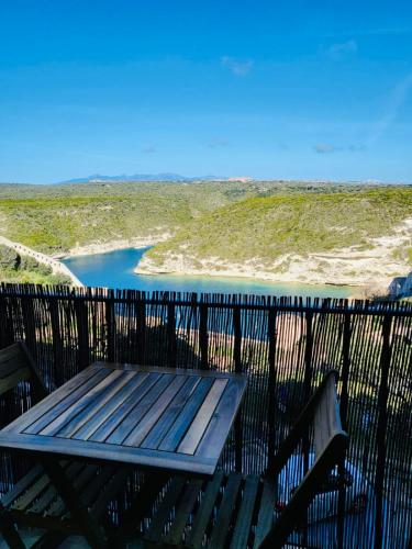 un banc en bois assis à côté d'une masse d'eau dans l'établissement Merveille de loft vue mer Citadelle de Bonifacio, à Bonifacio