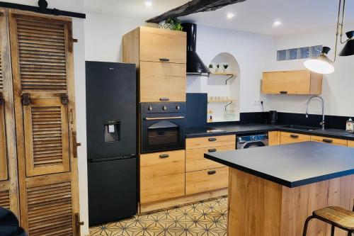 a kitchen with a black refrigerator and wooden cabinets at Location merveille de loft vue mer Bonifacio in Bonifacio