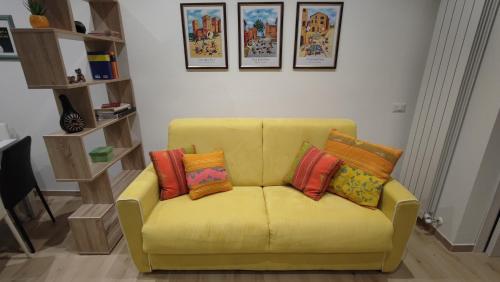 a yellow couch with four colorful pillows on it at Il Loft di Pieve in Città della Pieve