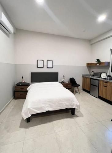 1 dormitorio con 1 cama blanca y cocina en Lofts, en Villahermosa