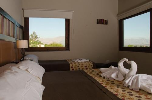 a hotel room with two beds and two windows at Munay Hotel Cafayate in Cafayate