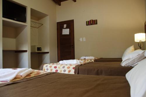 a hotel room with two beds and a television at Munay Hotel Cafayate in Cafayate