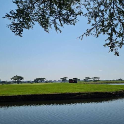a park with a lake and a house in the distance at Apartment in Entebbe 2 in Wakiso
