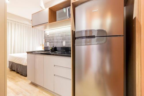 a stainless steel refrigerator in a kitchen with a bed at Charlie Uwin Brooklin in Sao Paulo