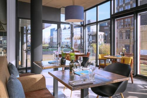 un restaurante con mesas, sillas y ventanas grandes en Stadshotel Doesburg en Doesburg