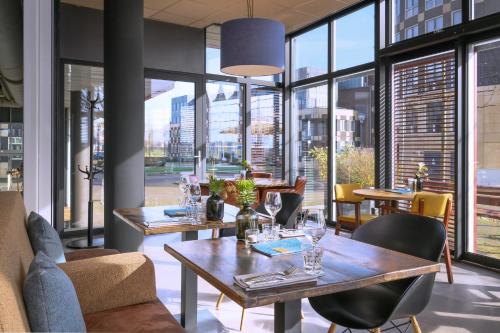 a restaurant with tables and chairs and large windows at Stadshotel Doesburg in Doesburg