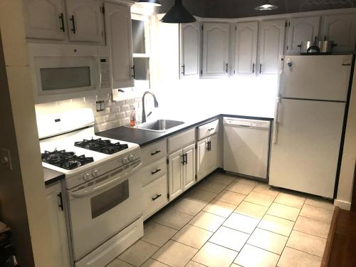 a kitchen with white cabinets and a stove and refrigerator at The John Randall House in Provincetown