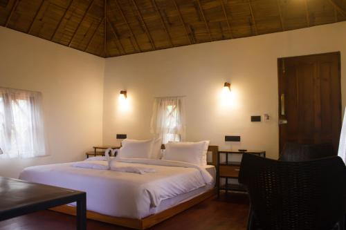 a bedroom with a bed with white sheets and pillows at GAIRAH RESORT in Mundakāyam