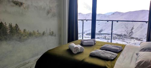 古道里的住宿－Segreto Apartments New Gudauri，窗户间里一张带毛巾的床
