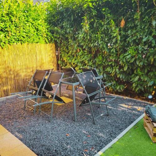 deux chaises et une table devant une haie dans l'établissement T2 COSY&CALME proche PARIS/ORLY, à La Ville-du-Bois