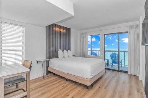 a white bedroom with a bed and a balcony at Grande Beach Resort in Myrtle Beach