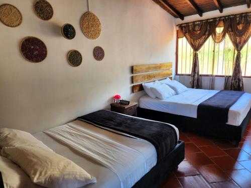 a bedroom with two beds and a window at Hotel Campestre Palmas del Zamorano in San Gil
