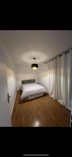 a bedroom with a white bed and a window at Spacieux appartement Paris/Stade De France/CDG in La Courneuve