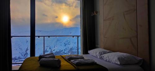a bed in a room with a large window at Segreto Apartments New Gudauri in Gudauri