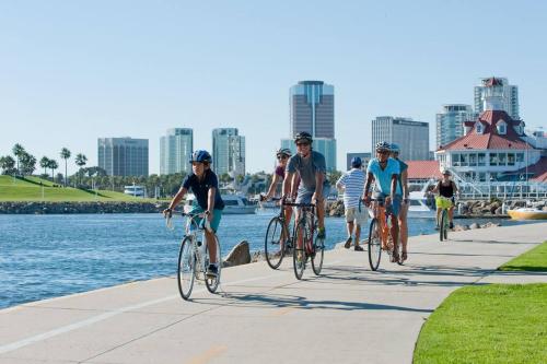 a group of people riding bikes on a sidewalk by the water at Historic Hm Mins to Beach, Convention Ctr Parking LB E in Long Beach