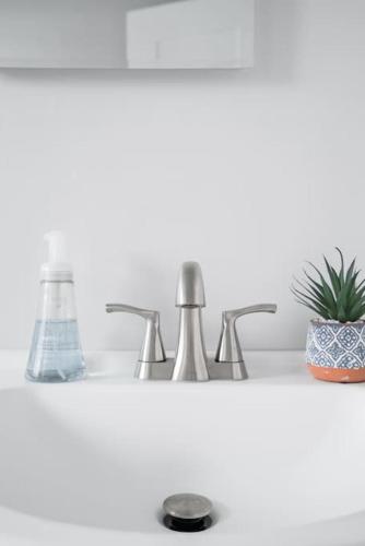 a bathroom sink with two faucets and a plant at Historic Hm Mins to Beach, Convention Ctr Parking LB E in Long Beach