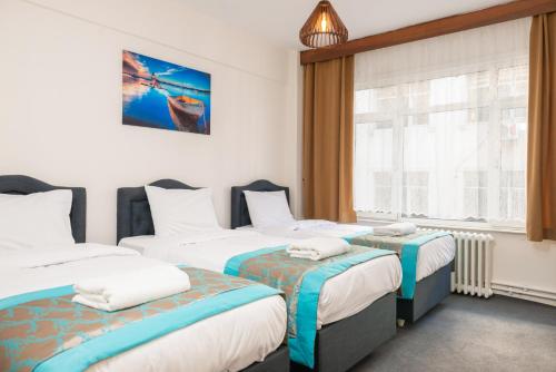 イスタンブールにあるBig Family Apartのベッド3台と窓が備わるホテルルームです。