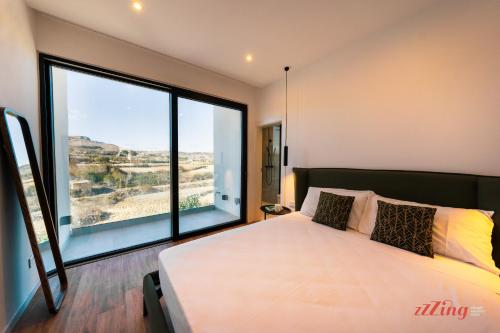 um quarto com uma cama grande e uma janela grande em A Stylishly Dreamy Gozo Apartment em Marsalforn