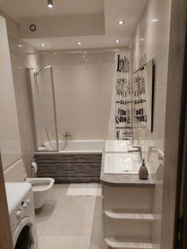 uma casa de banho com um lavatório, uma banheira e um WC. em Apartament em Legionowo