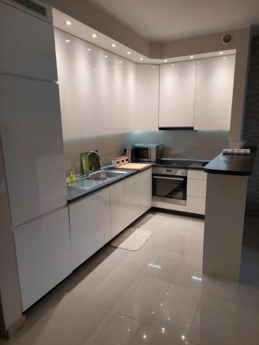 a kitchen with white cabinets and a sink at Apartament in Legionowo