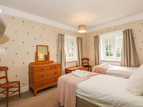 een slaapkamer met twee bedden, een ladekast en een spiegel bij Beckhythe Cottage in Cromer