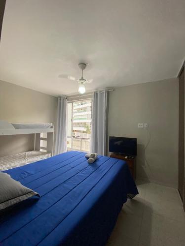 sypialnia z niebieskim łóżkiem i oknem w obiekcie Apartamento à 3 minutinhos da praia do forte w mieście Cabo Frio