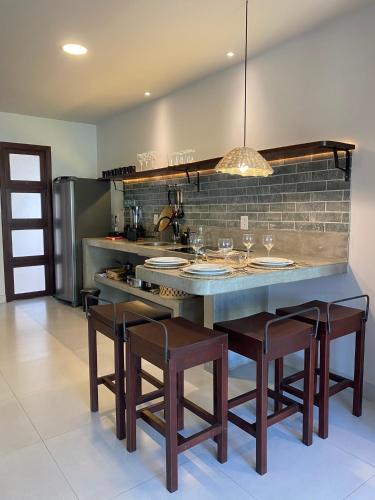 a kitchen with a counter with chairs and a table at Zenhousepipa in Pipa