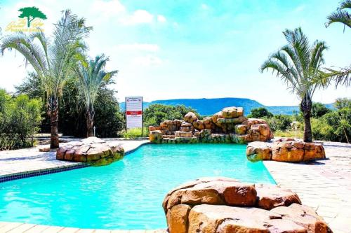 a large swimming pool with rocks and palm trees at Grand Bay Botanical Gardens & Resort 