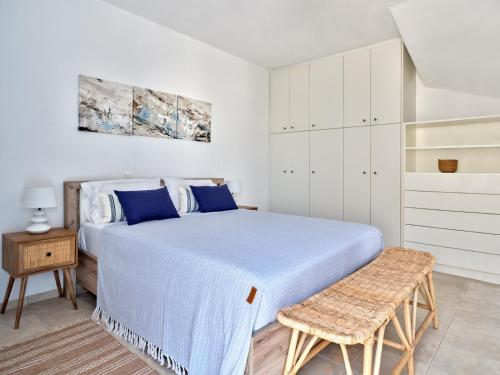 een witte slaapkamer met een bed en een kruk bij Paros Luxury Villa 2mins from the beach in Piso Livadi