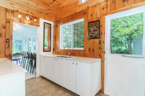 a kitchen with white cabinets and windows in a house at The Lakehouse in Carnarvon