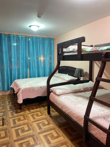 two bunk beds in a room with blue curtains at Hostal Costa Linda Salinas in Salinas