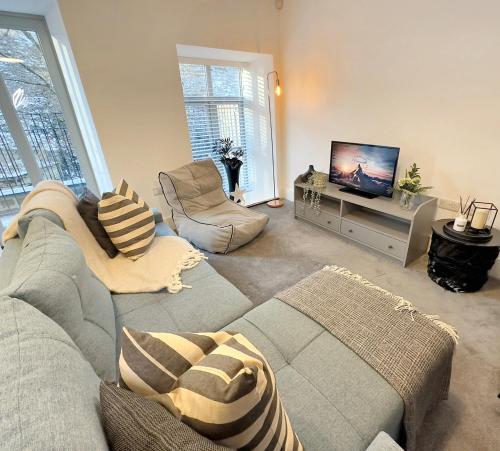 a living room with a couch and a flat screen tv at The Yorkshire Hosts - The Water Mill in Haworth