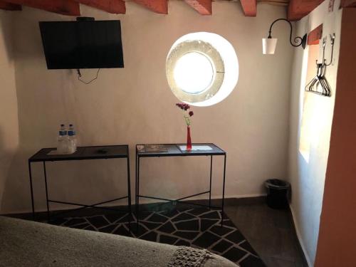 a room with two tables and a tv and a window at Hotel Boutique Posada La Basilica in Pátzcuaro