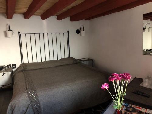 a bedroom with a bed and a vase with flowers at Hotel Boutique Posada La Basilica in Pátzcuaro