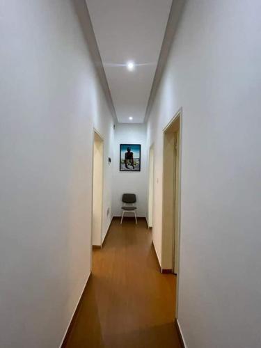 un pasillo con paredes blancas y una silla en una habitación en Entrée personnelle fidjrossè, en Cotonou