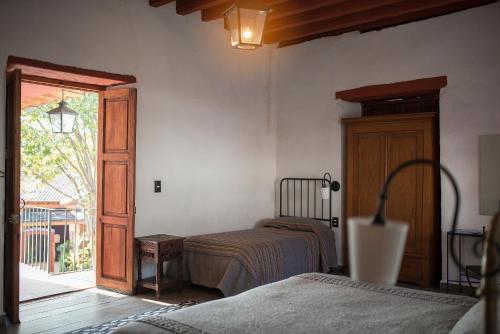 a bedroom with two beds and a sliding glass door at Hotel Boutique Posada La Basilica in Pátzcuaro