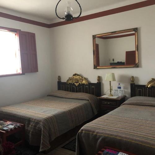 a bedroom with two beds and a mirror on the wall at Hotel Boutique Posada La Basilica in Pátzcuaro