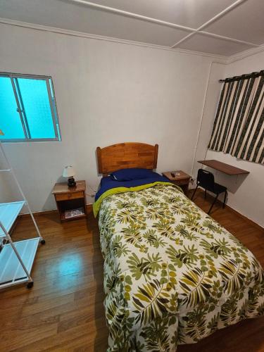 a bedroom with a bed with a green and white comforter at POSADA COPACABANA in Tocopilla