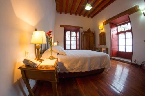 a bedroom with a bed and a table with a lamp at Hotel Boutique Posada La Basilica in Pátzcuaro