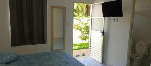 a bedroom with a bed and a window with a toilet at Suítes com piscina Praia do Forte Tomas in Praia do Forte