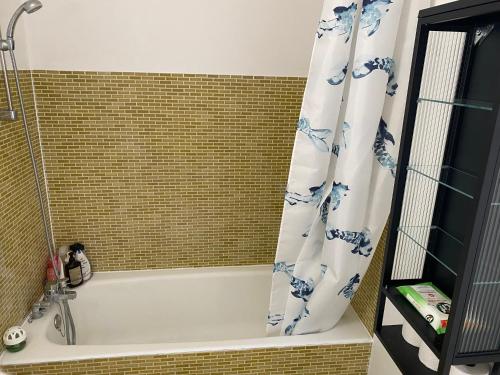 a bathroom with a bath tub with a shower curtain at apartment close to La Defense in Nanterre