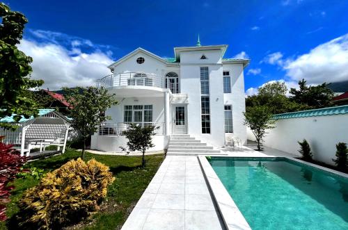 una casa blanca con piscina frente a ella en Qafqaz Manor Kibana en Gabala