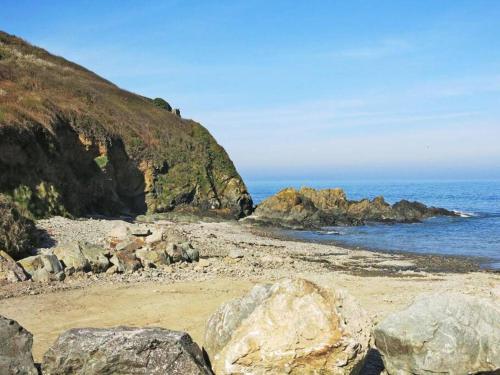 a beach with some rocks and the ocean at Appart vue mer-au pied du chemin de randonnée " Bassan" in Planguenoual