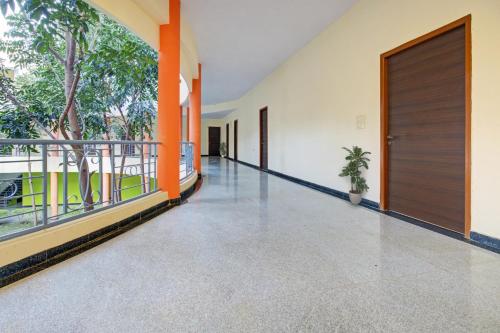 an empty corridor of a building with orange columns and a door at Super OYO RK Club House in Kammasandra