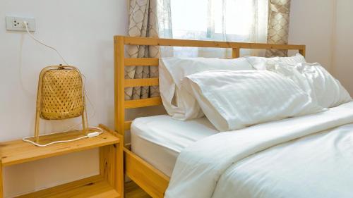 a bed with white sheets and pillows next to a window at Baan Casita With Private Seaside Cottage in Hua Hin