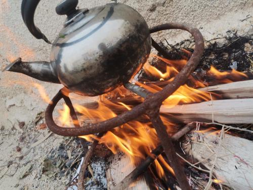 a metal tea kettle on top of a fire at Dana Nabil Ecu Camp House - Main Gate Dana nature reserve in Dana