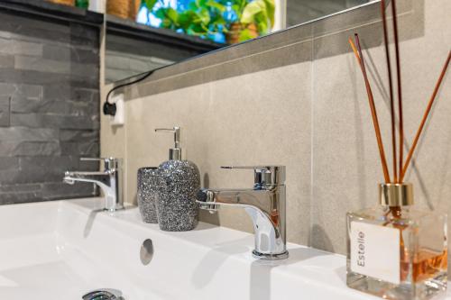 een wastafel in de badkamer met 2 kranen en een spiegel bij Watervillashiraz in Aalsmeer