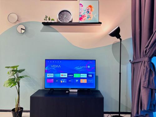 a flat screen tv sitting on top of a black cabinet at Urban Suite Cozy Family Homestay at Georgetown by URBAN STAYCATION HENG LOD in Jelutong