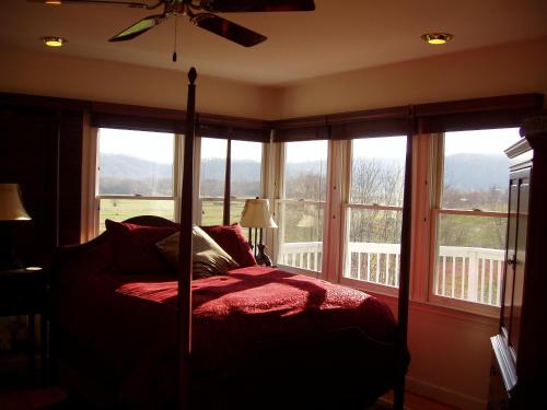 una camera con un letto di fronte alle finestre di Fairhill Farm Country Vacation Rentals a Stanardsville