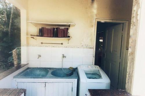 a dirty bathroom with a sink and a washing machine at Canto sossego casa independente a passos do mar in Búzios